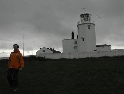 Bloke in Bright Orange Jacket in Front of Lighthouse